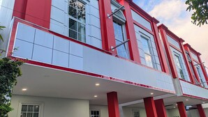 A modern building with a red and white facade, large windows, and a flat roof. - Rizki Kost Exclusive II (Depok)