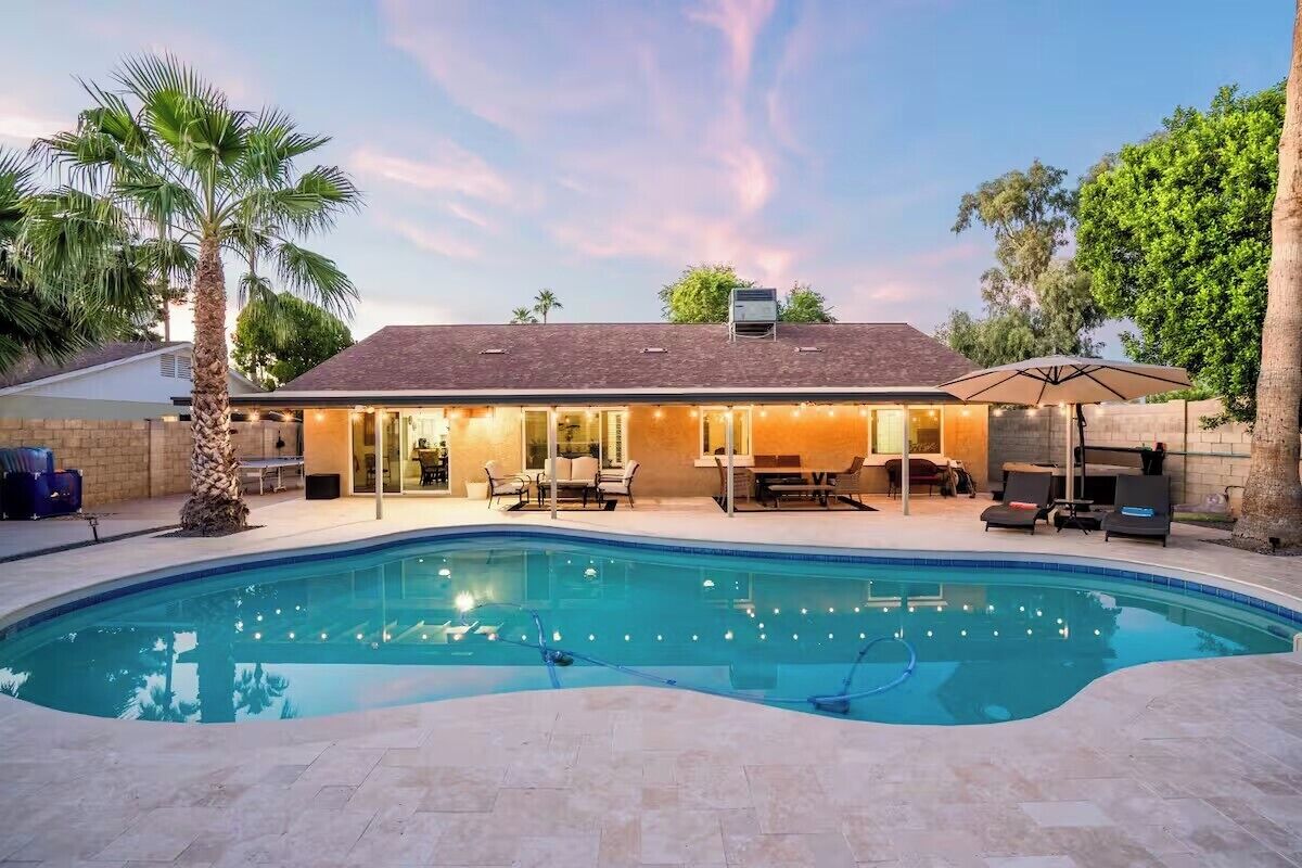 A house with a swimming pool, outdoor seating, and a covered patio area.
