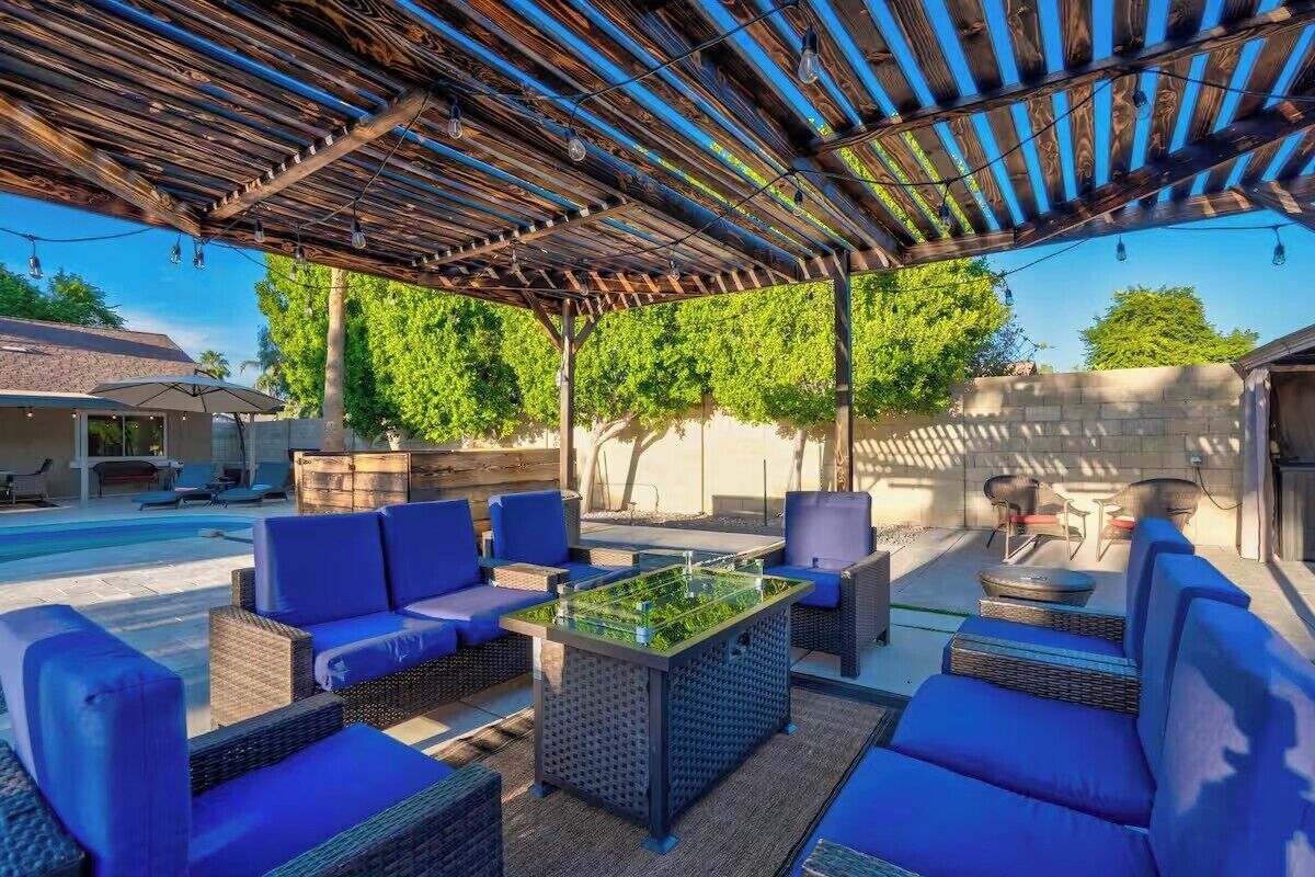 An outdoor patio with wicker furniture, a foosball table, and a pergola overhead.