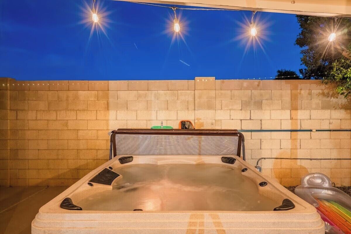 Un jacuzzi con pared de ladrillo de fondo e iluminación colgante.
