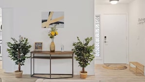 A reception area with a wooden console table, two potted plants, a welcome sign, and a framed picture. - Backyard Paradise in Chandler (Chandler)
