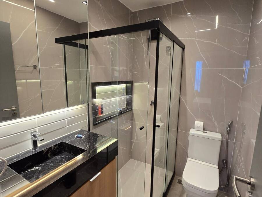 Un bagno moderno con doccia vetro, un water e un mobile lavabo.