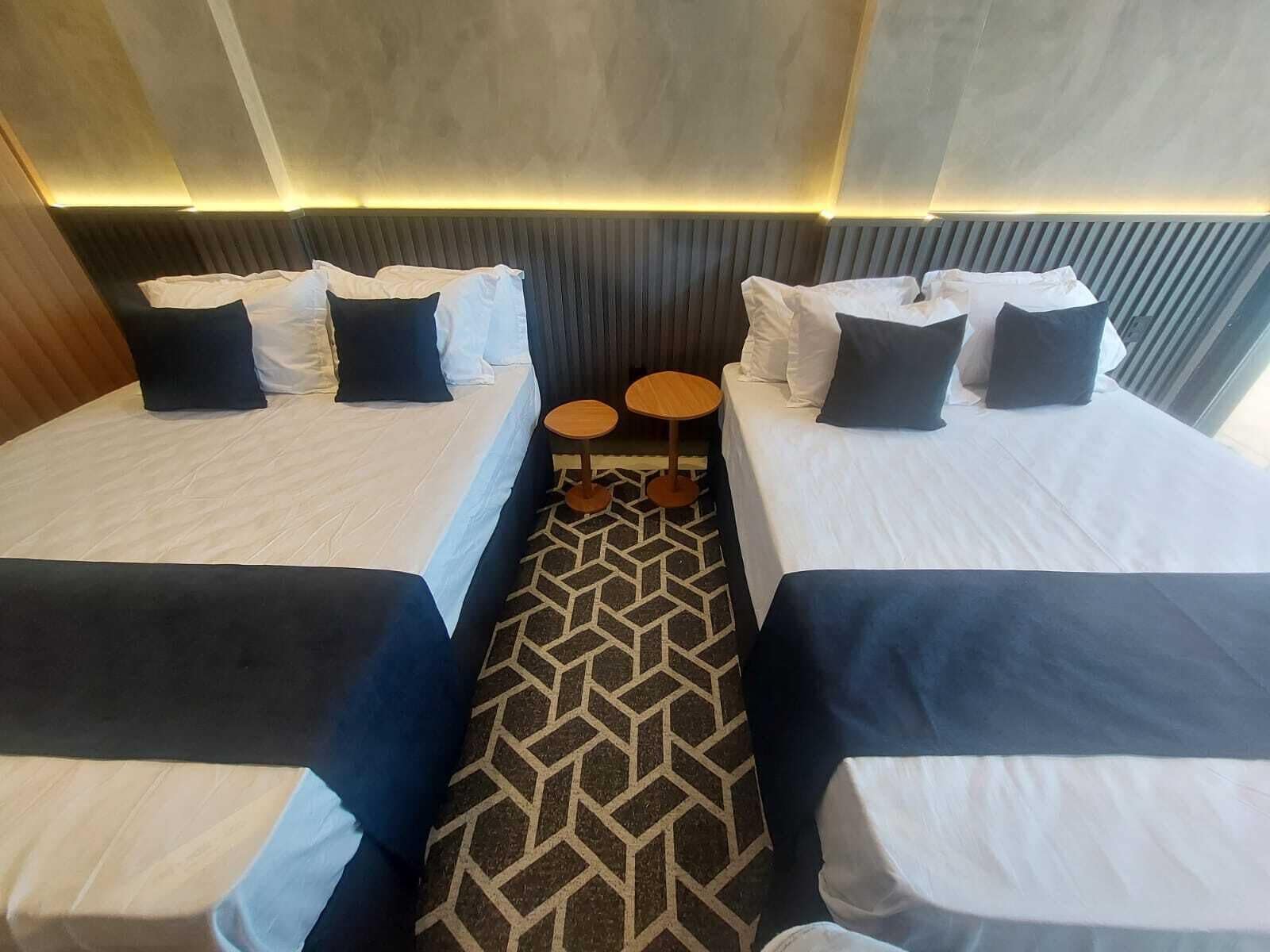 Una habitación de hotel con dos camas, una mesita redonda y suelo estampado.