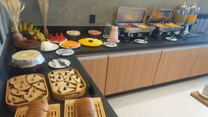 A buffet with various food items and a juice dispenser. - VHome Flat Hotel (Macaé)