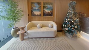 A cozy living room with a sofa, a Christmas tree, and two framed beach paintings. - VHome Flat Hotel (Macaé)