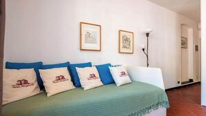 Una habitación con una cama, una manta verde y almohadas con el texto 'Santa Margherita'. Hay dos cuadros en la pared.