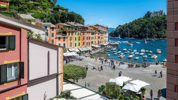 Un pueblo costero con edificios de colores, un puerto deportivo y un paseo marítimo.