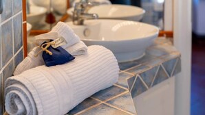 Un baño con un lavamanos blanco y un perchero con una toalla doblada y una almohada azul.