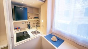 A compact kitchenette with a built-in stove, sink, and shelves for storage. - La Casetta by PortofinoVip [AC-Super central]. (Portofino)