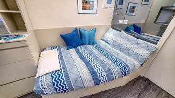 Un dormitorio con cama, almohadas, cómoda y espejo.