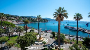 Une ville côtière dotée d’un port de plaisance, de palmiers et d’une statue en premier plan.