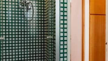 A bathroom with checkered green and white tiles, a shower with a wooden seat, and a wooden door.