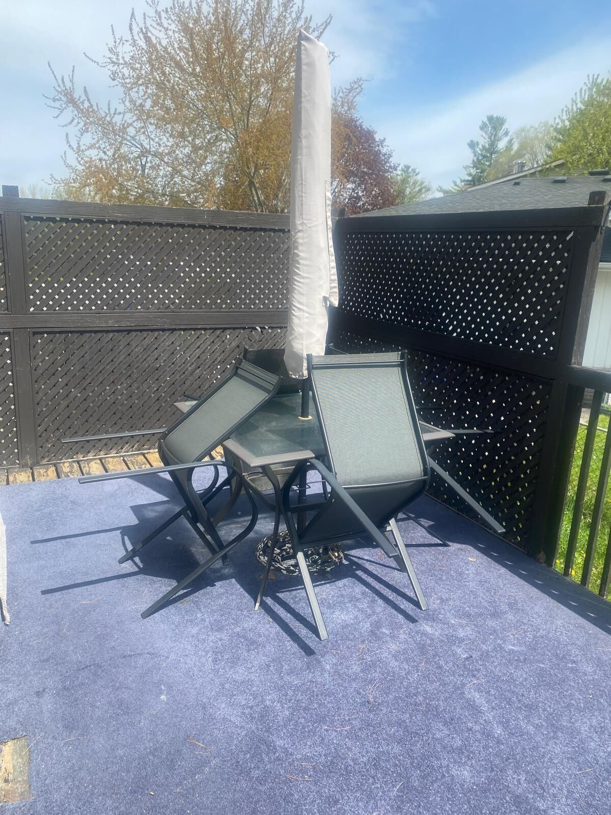 Pihalla on patio, jossa on pöytä ja tuoleja, aurinkovarjo ja aita.