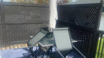 Pihalla on patio, jossa on pöytä ja tuoleja, aurinkovarjo ja aita.