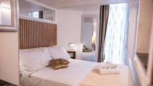 Una camera d'albergo con un letto, un comodino, uno specchio e una finestra con tende.