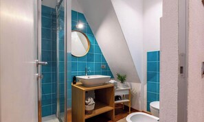 Ein Badezimmer mit Waschbecken in Weiß, blauen Fliesen, einem Holzkosmetikschrank, einem Spiegel und einer Dusche.
