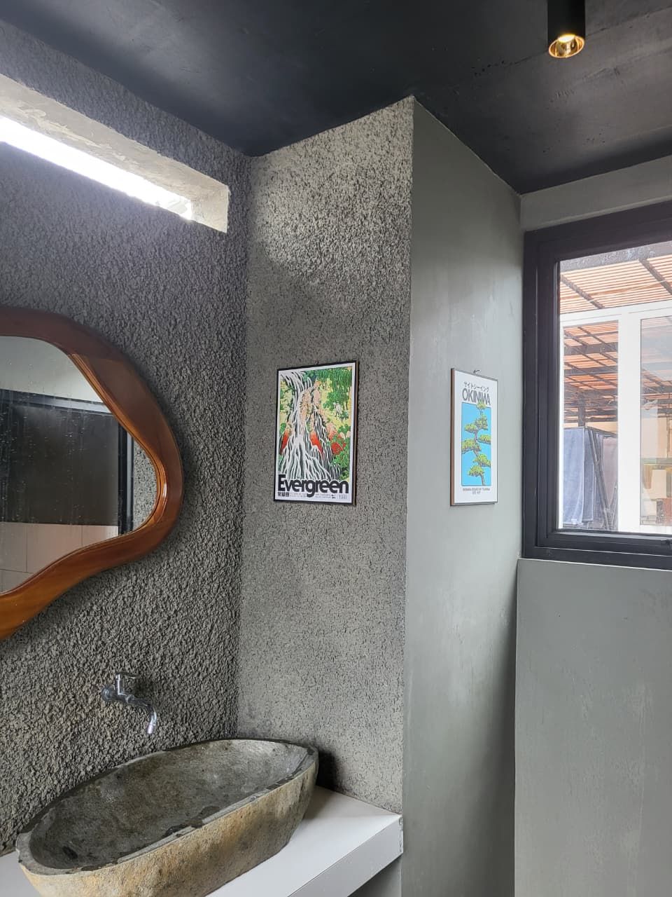 A bathroom with a stone sink, a wooden-framed mirror, and two framed pictures on the wall.