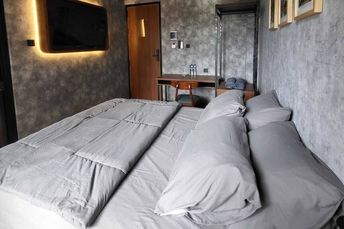 Un dormitorio moderno con una cama grande, un escritorio y un televisor de pantalla plana montado en la pared.