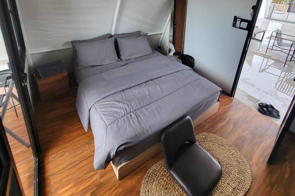 Habitación tipo tienda de campaña con una cama, una silla y una lámpara colgante.