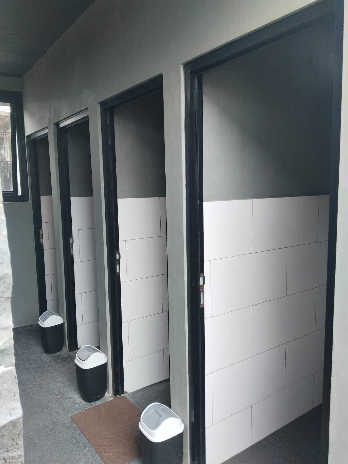 A hallway with doors, trash bins, and a doormat.