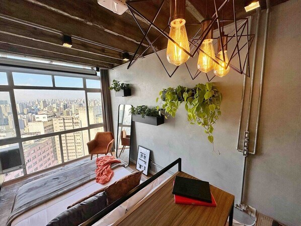 A room with a large window, a wooden bench, a table, and hanging plants. - 2802B (São Paulo)