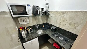A compact kitchen with a microwave, coffee maker, and a small refrigerator. - 0516B (São Paulo)