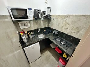 Eine kleine Küche mit Mikrowelle, Kaffeemaschine und kleinem Kühlschrank.