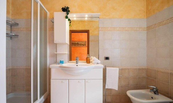 Un baño con ducha, lavamanos y espejo.