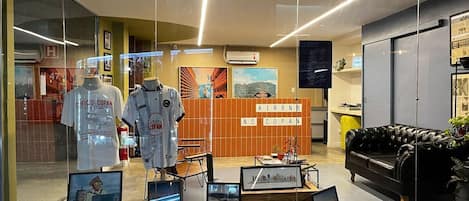 Un hall d’hôtel avec un comptoir d’accueil, des tableaux représentant des vues de la ville, et un canapé en cuir noir.