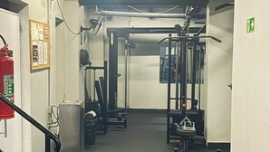 A gym with exercise equipment, a fire extinguisher, and a stairway.