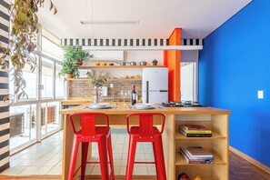 A modern kitchen with a wooden island, red bar stools, and a blue accent wall. - 0285F (São Paulo)