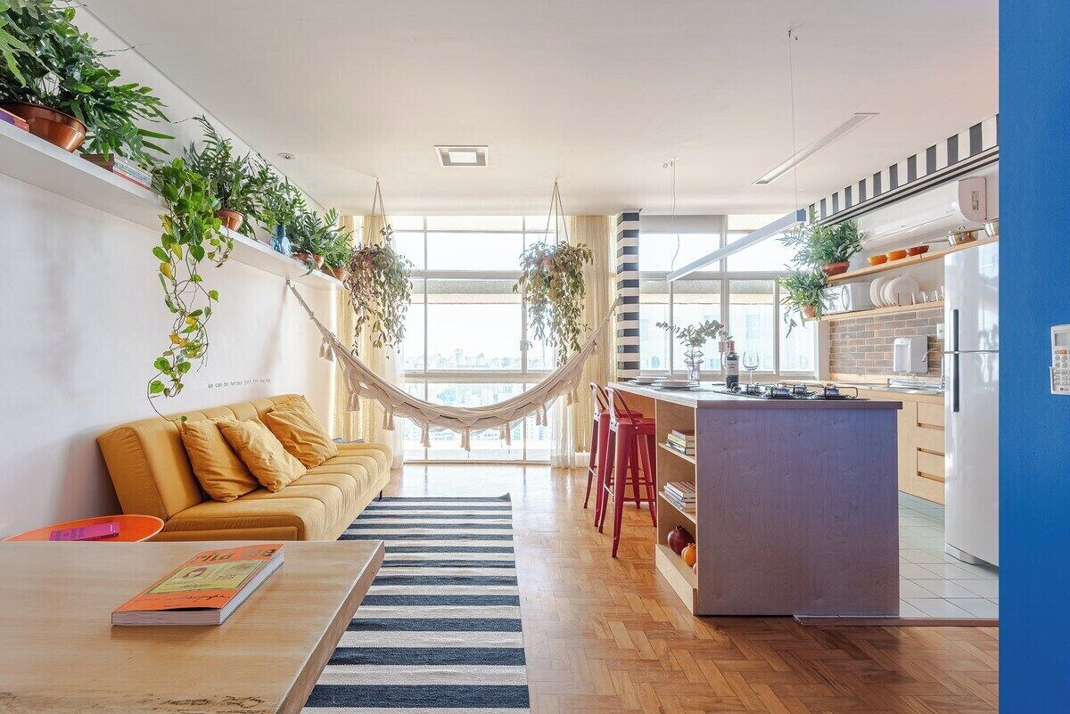 Eine moderne Küche mit einer zentralen Kochinsel, ein Essbereich mit einer Couch und einer Hängematte.