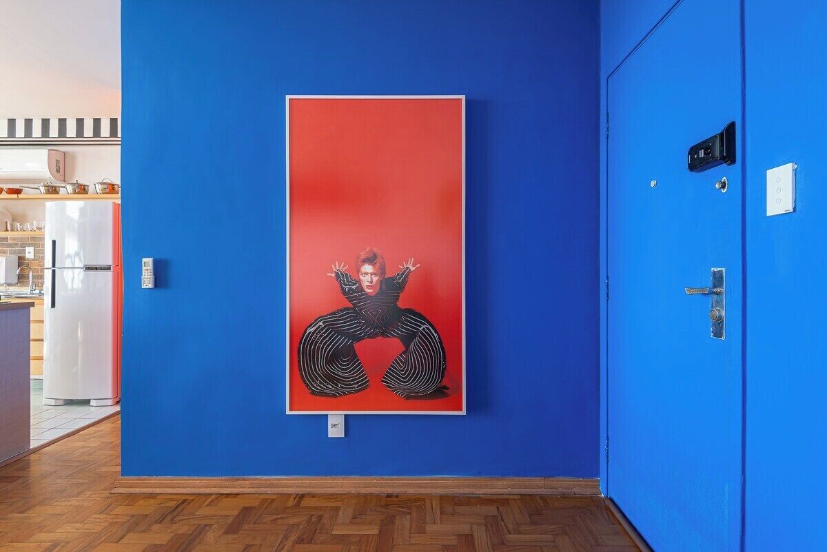 A hallway with a blue wall and a framed artwork.