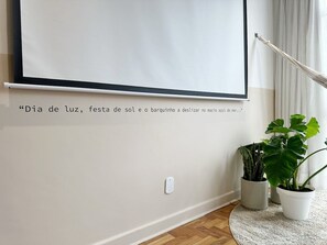 A room with a projector screen, a white wall, and two potted plants. - 1609B (São Paulo)