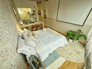 Ein Schlafzimmer mit einem Bett, einem Schreibtisch, einer Gitarre und einem Blumentopf.