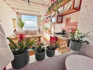 Un soggiorno moderno con cucina, zona pranzo e un'ampia finestra vista città.