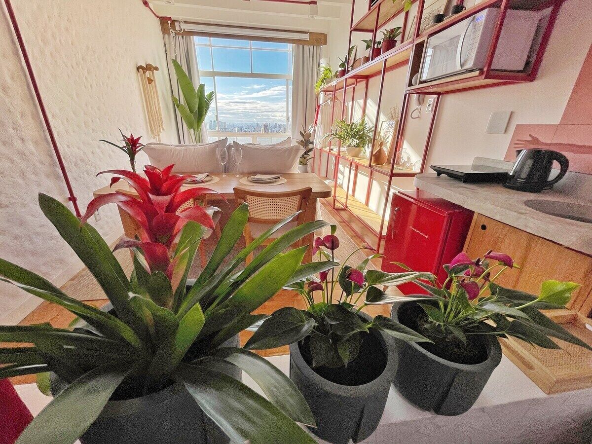 Een moderne keuken met een eetgedeelte, potplanten en uitzicht op de stad.