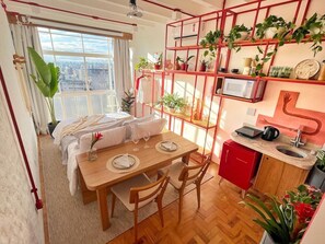 Ein kompakter Wohnbereich mit Essplatz, Küchenzeile und einem Bett mit Blick auf die Stadt.