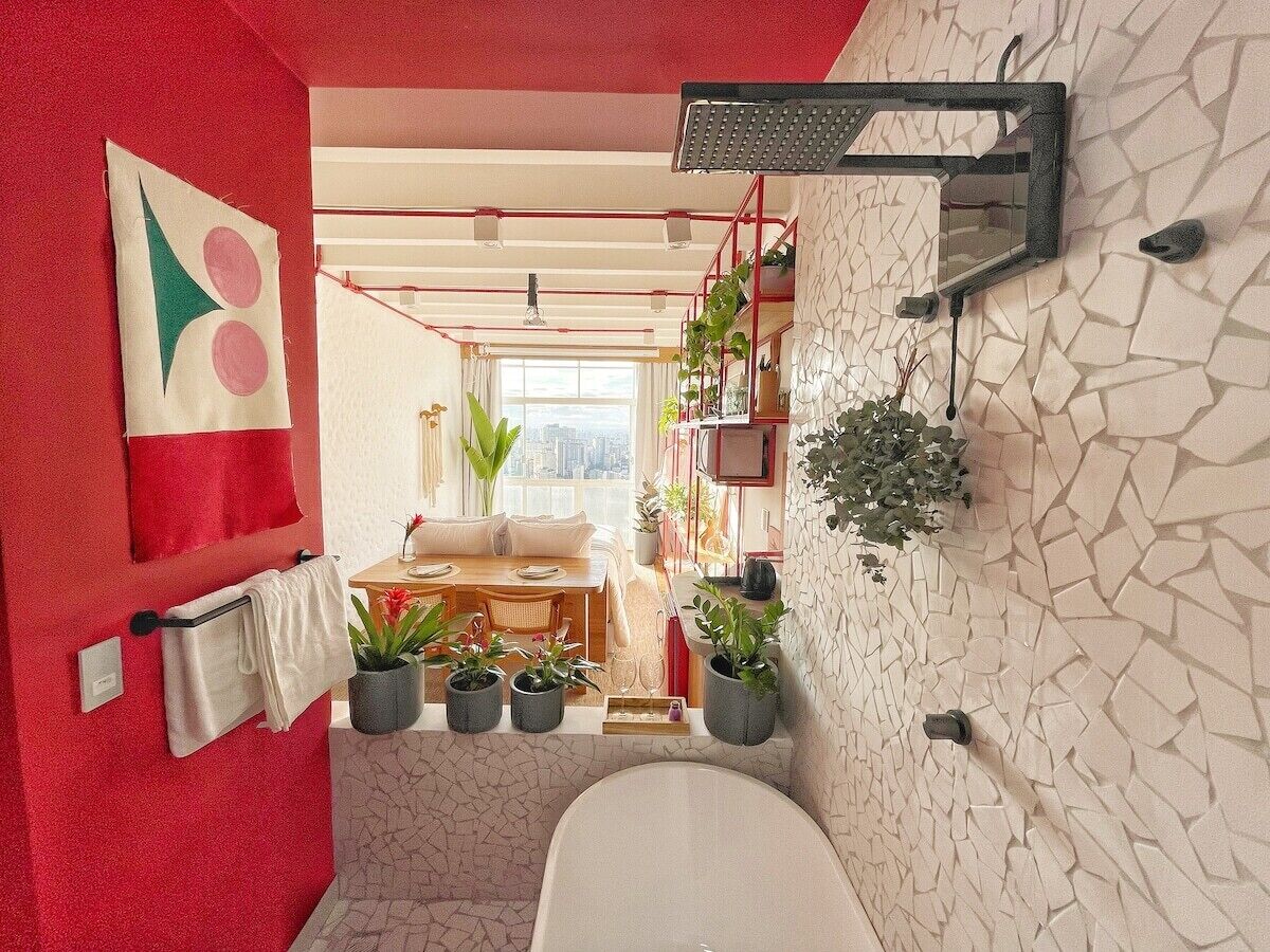 Un baño con una bañera blanca, un toallero rojo y una zona de ducha.