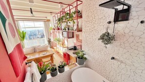 Uma casa de banho moderna com banheira, chuveiro e prateleira na parede com plantas.