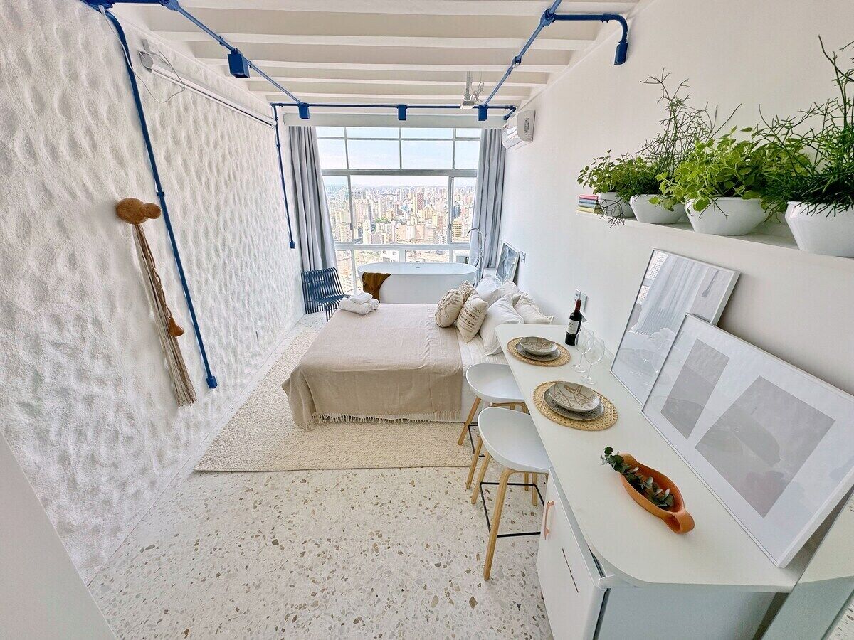Ein Schlafzimmer mit Bett, Schreibtisch und Fenster mit Blick auf die Stadt.