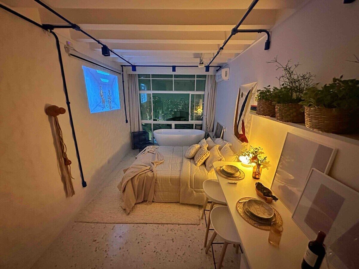 Un dormitorio pequeño con cama, mesita de noche y ventana.