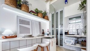 Una cocina moderna con armarios blancos, microondas integrado y una barra con taburetes.