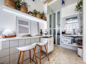 A modern kitchen with white cabinetry, a built-in microwave, and a bar area with stools. - 3105B (São Paulo)