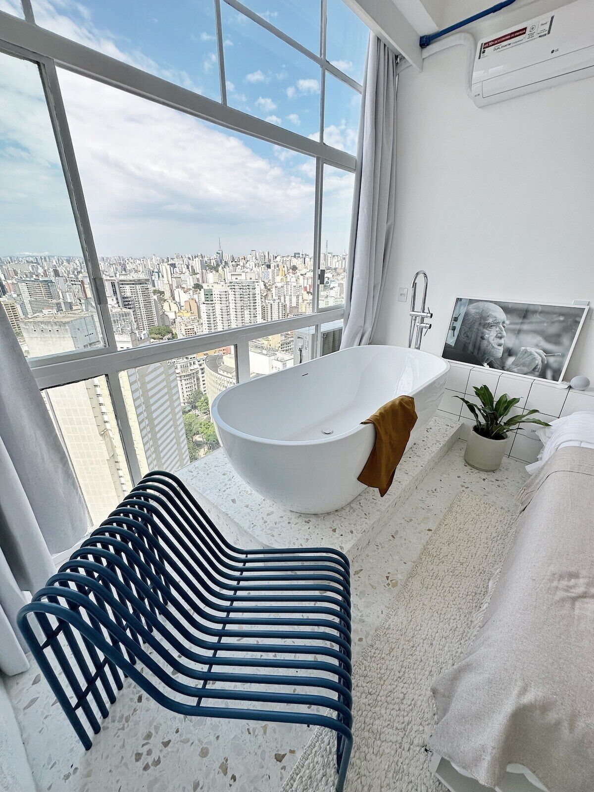 A modern bathroom with a large bathtub, a shower, and a view of a cityscape.