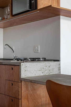 A kitchen with a stainless steel sink, a gas stove, wooden cabinets, and a microwave above the counter. - 3017B (São Paulo)