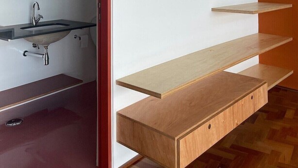 Ein modernes Badezimmer mit integriertem Waschbecken, Holzregalen und einer Pendelleuchte.