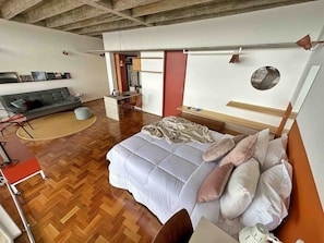 A modern bedroom with a large bed, a small desk, a sofa, and a dining area. - 3017B (São Paulo)