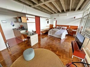 Een ruime kamer met een groot bed, een bureau en een kitchenette.