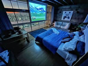 Ein Schlafzimmer mit einem großen Bett, einem Fernseher und Blick auf die Stadt.